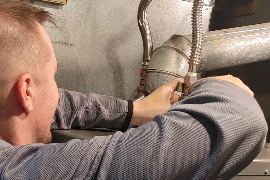 Plumber working on gas water heater piping and controls related to Worn anode rod from a Monrovia water heater
