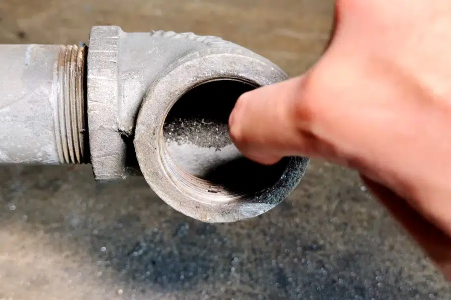 Corroded cast iron pipe section with visible rust and buildup related to Channeled cast iron drain pipe