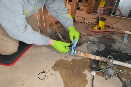 Sump pump basin and pump components being fitted near a foundation related to Library Park Area neighborhood