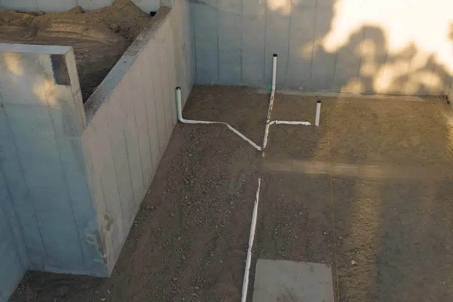 Crawlspace plumbing with drain and supply lines below the floor related to Careful repipe routing in a Monrovia landmark home